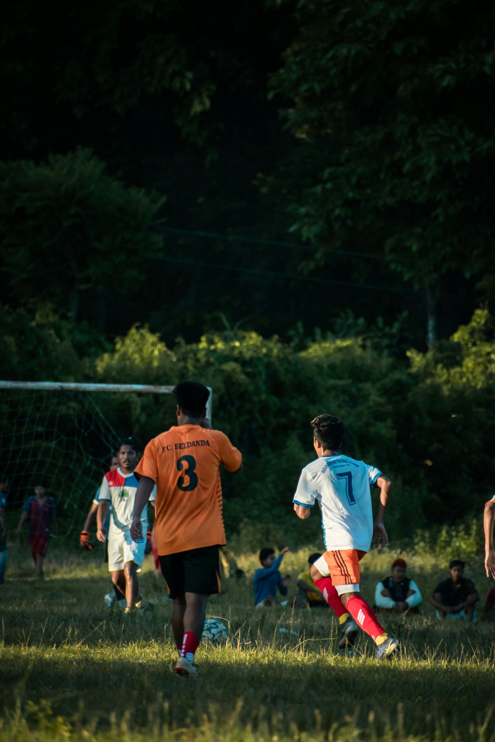 Players competing in a lively soccer game on an outdoor grassy field.